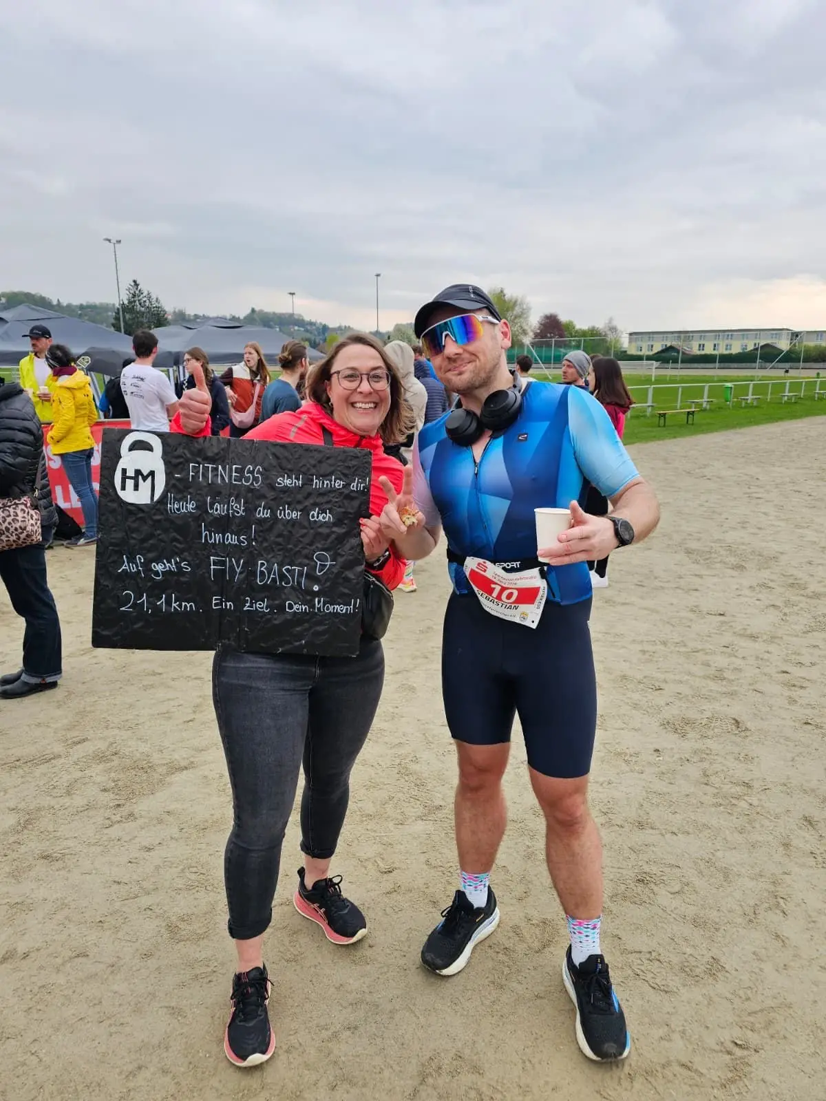 Zwei Läufer mit handgeschriebener HM-Fitness-Tafel im Zielbereich des Sparkassen Halbmarathons